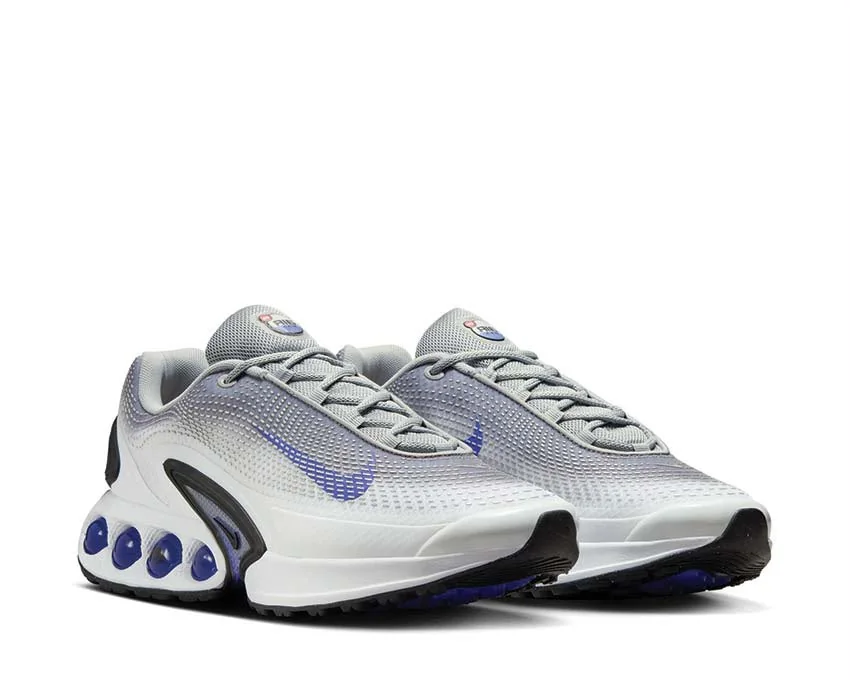 Nike Air Max Dn Light Smoke Grey / Photon Dust / Persian Violet / Black — Chaussures Oriol Shoes Abomey-Calavi. Paire de baskets basses Nike en mesh gris clair et blanc, logos Swoosh violets, lacets gris, semelle blanche avec éléments d’amorti violets et noirs visibles au talon et sous la semelle.