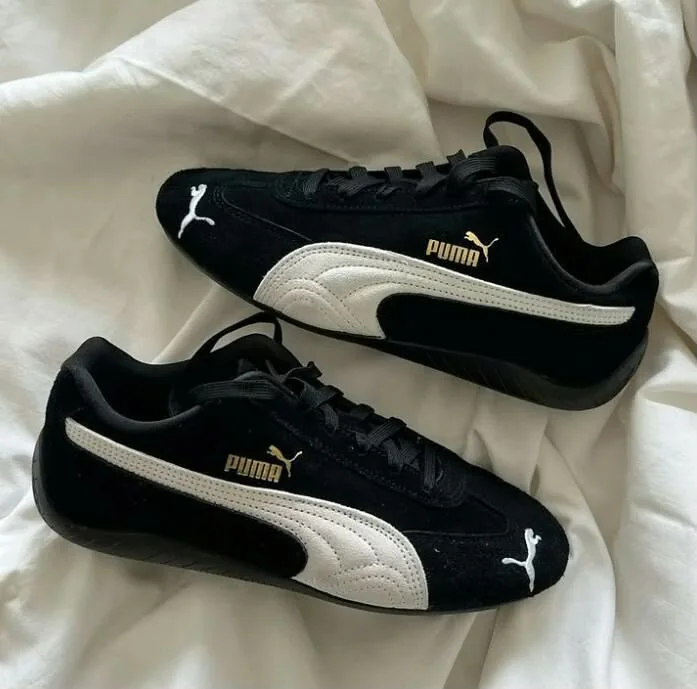 PUMA Speedcat OG PUMA Black / PUMA White — Chaussures Oriol Shoes Abomey-Calavi. Paire de baskets basses noires, empiècements latéraux et logos Puma blancs, marquage Puma doré, lacets noirs, semelle noire ; matière visuellement synthétique ou textile, non vérifiable avec certitude.