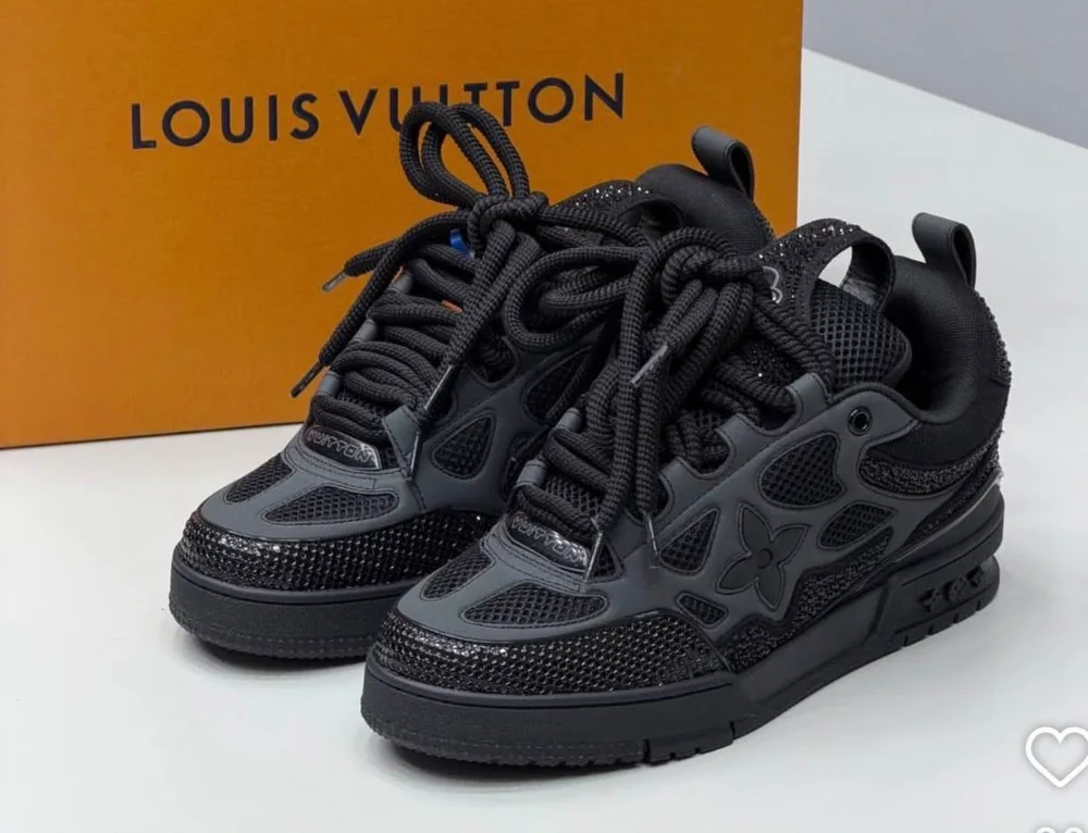 Chaussure de la sélection Oriol Shoes — Chaussures Oriol Shoes Abomey-Calavi. Paire de baskets montantes noires, lacets noirs épais, empiècements en mesh et empiècements synthétiques ton sur ton, motif fleur latéral, semelle noire crantée ; 